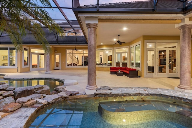 pool at dusk with a jacuzzi, a patio, an outdoor living space, glass enclosure, and ceiling fan