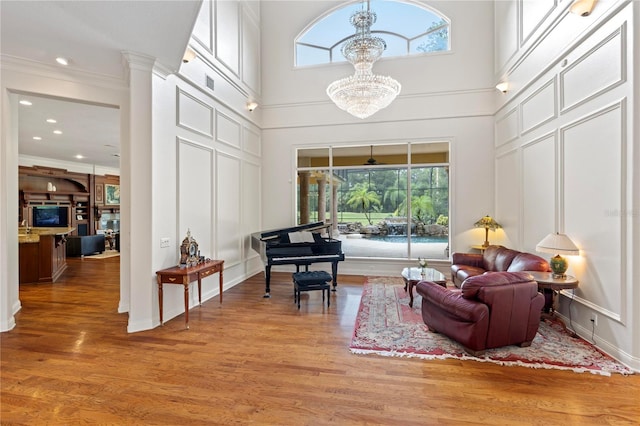 living area featuring ornamental molding, a high ceiling, light hardwood / wood-style floors, and a wealth of natural light