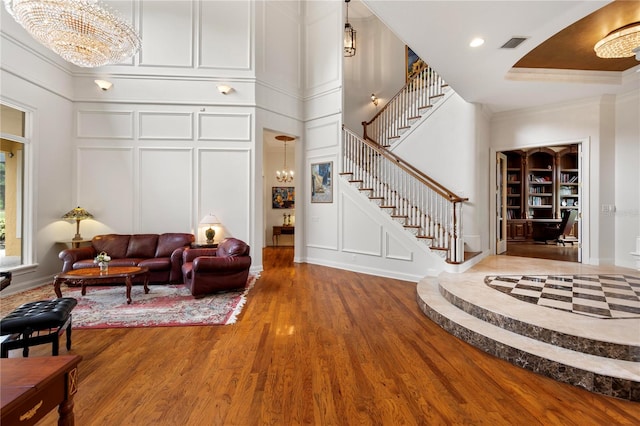 living room with ornamental molding, wood-type flooring, and built in shelves