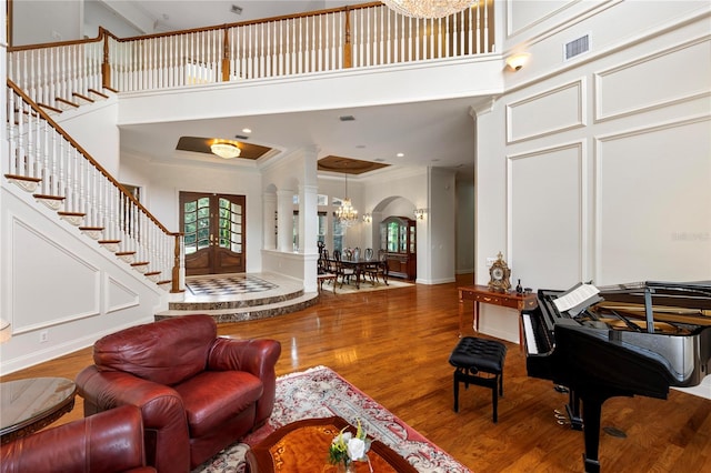 interior space with hardwood / wood-style flooring, crown molding, a towering ceiling, and a notable chandelier