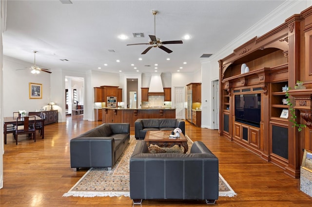 living room featuring wood-type flooring, crown molding, and ceiling fan