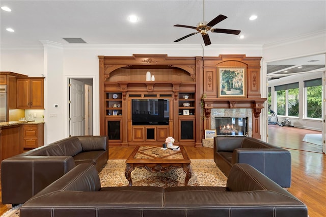 living room with crown molding, light hardwood / wood-style floors, ceiling fan, and a premium fireplace