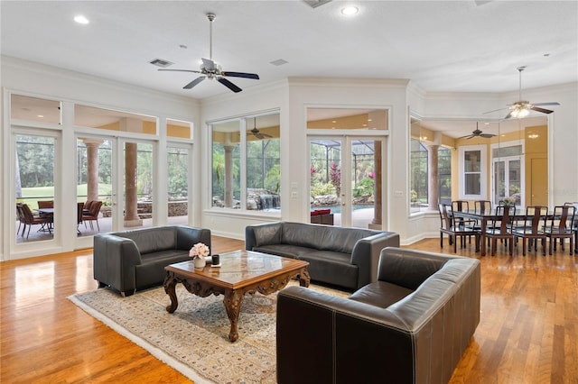 living room with light hardwood / wood-style flooring, ornate columns, and crown molding