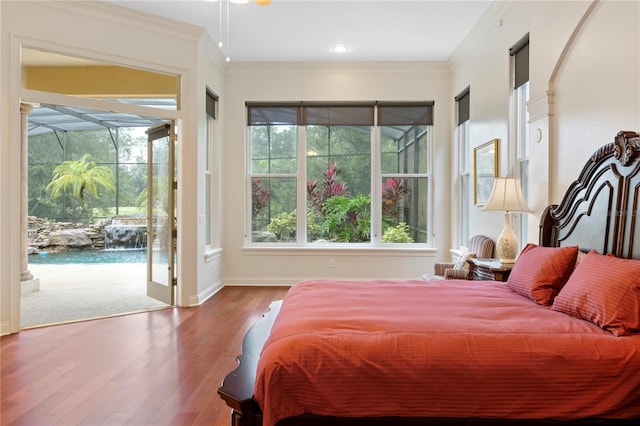 bedroom featuring access to outside, crown molding, hardwood / wood-style floors, and multiple windows