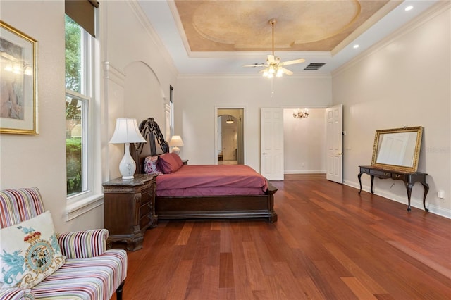 bedroom with multiple windows, a tray ceiling, and dark hardwood / wood-style floors