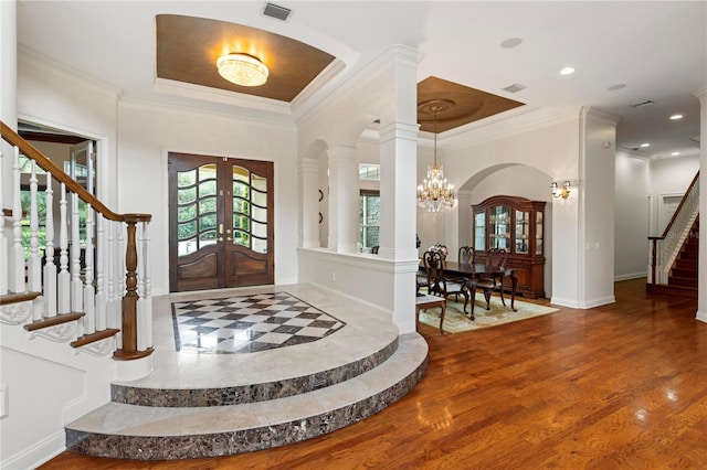 entryway with wood-type flooring, ornamental molding, an inviting chandelier, and french doors