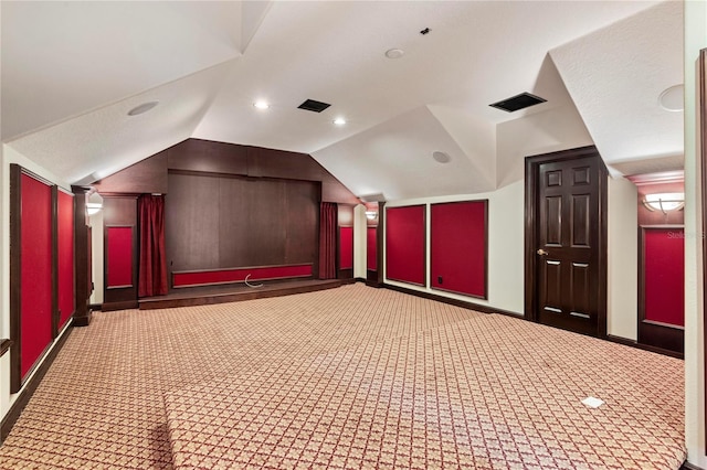 home theater room with vaulted ceiling and dark colored carpet