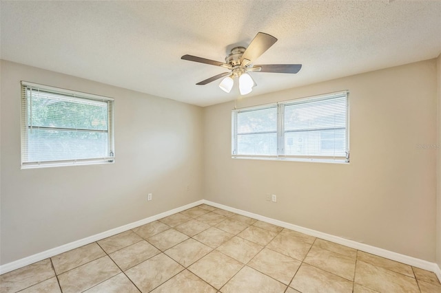 empty room featuring a textured ceiling, light tile patterned floors, and ceiling fan