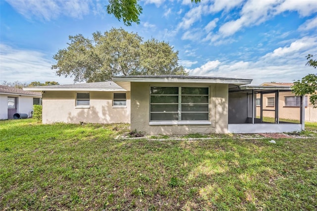 10226 Willow Dr, Port Richey, FL 34668 - rear view of house featuring a yard, stucco siding, and a sunroom