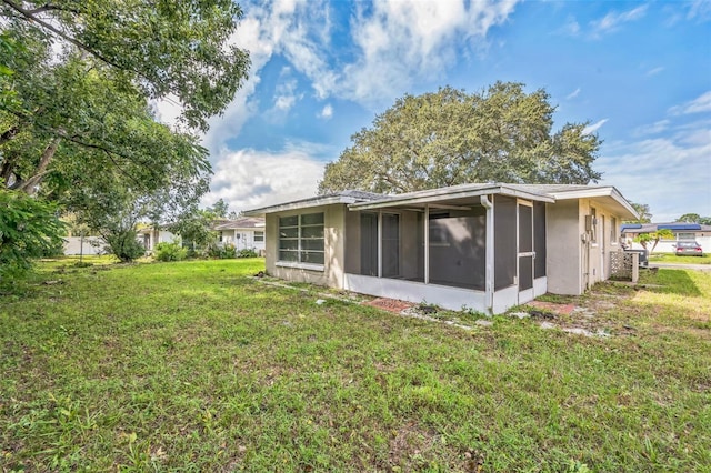 10226 Willow Dr, Port Richey, FL 34668 - back of property with a sunroom, stucco siding, and a lawn