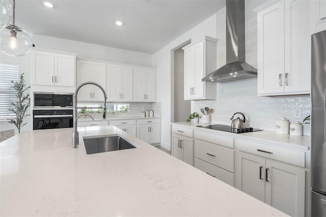 kitchen with white cabinets, sink, wall chimney exhaust hood, decorative backsplash, and appliances with stainless steel finishes