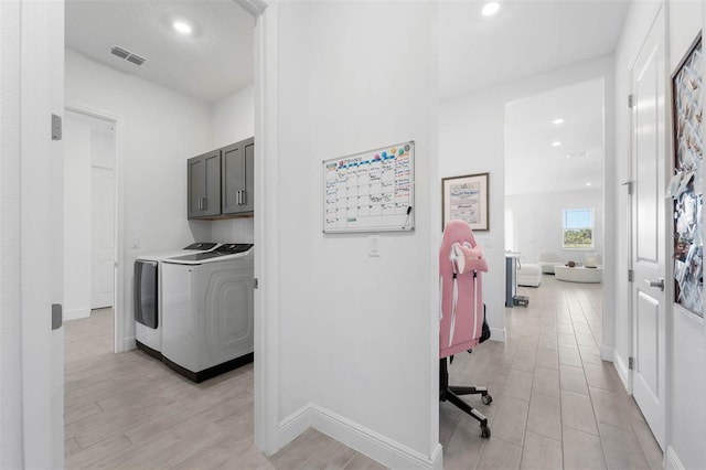 washroom with washer and dryer, cabinets, and light wood-type flooring