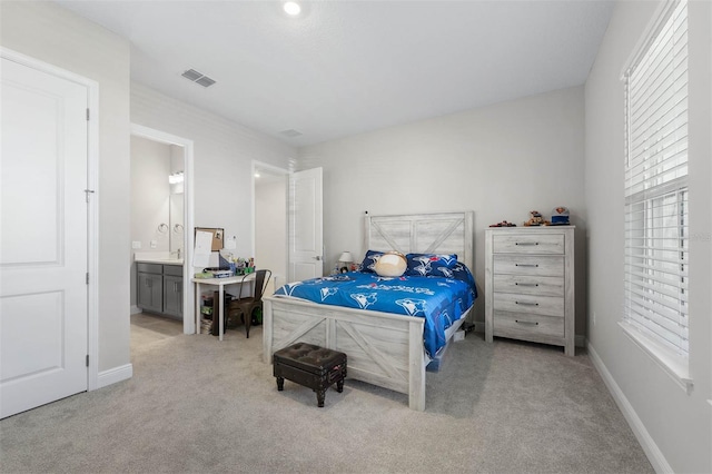 bedroom featuring ensuite bathroom and light carpet