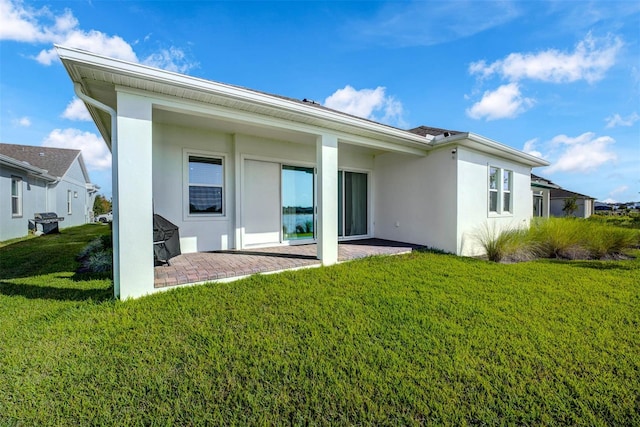 back of house with a lawn and a patio