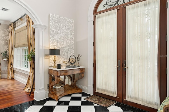 foyer entrance featuring decorative columns, ornamental molding, dark hardwood / wood-style floors, and french doors