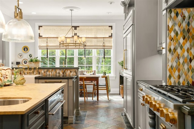 kitchen featuring an inviting chandelier, stainless steel appliances, decorative light fixtures, and crown molding