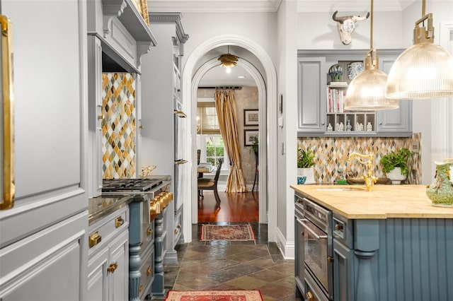 bar with hanging light fixtures, ornamental molding, wooden counters, tasteful backsplash, and stainless steel appliances