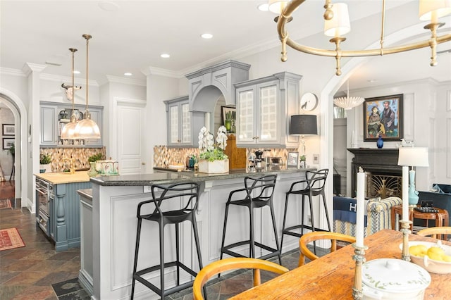 kitchen with ornamental molding, a kitchen bar, hanging light fixtures, and tasteful backsplash