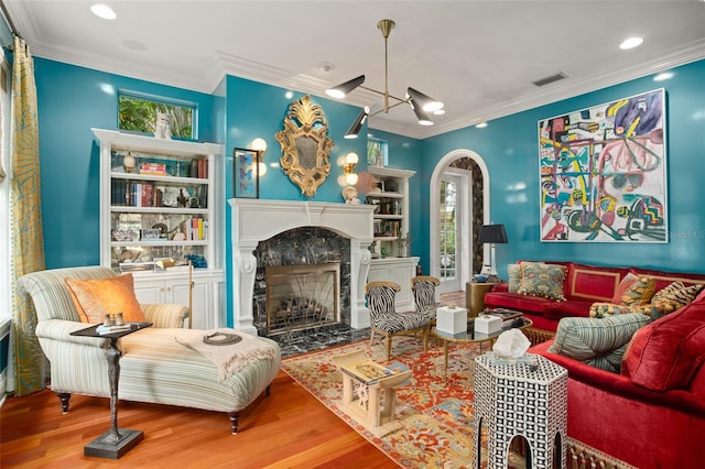 living room with ornamental molding, a premium fireplace, and hardwood / wood-style flooring