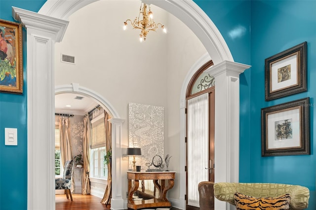 entrance foyer with wood-type flooring, a towering ceiling, and crown molding