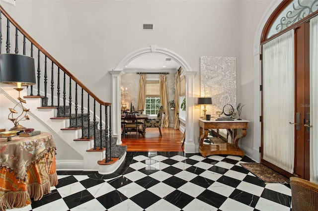 entrance foyer with french doors, crown molding, decorative columns, and a towering ceiling