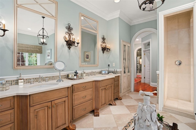 bathroom featuring tile patterned flooring, tiled shower, vanity, and crown molding