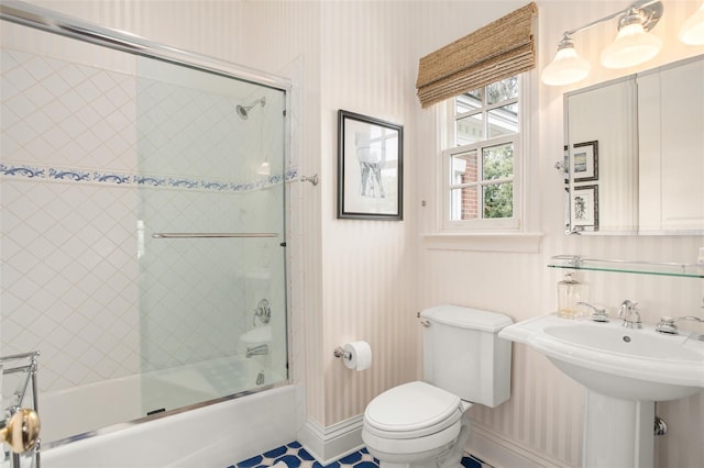 full bathroom with bath / shower combo with glass door, sink, tile patterned flooring, and toilet