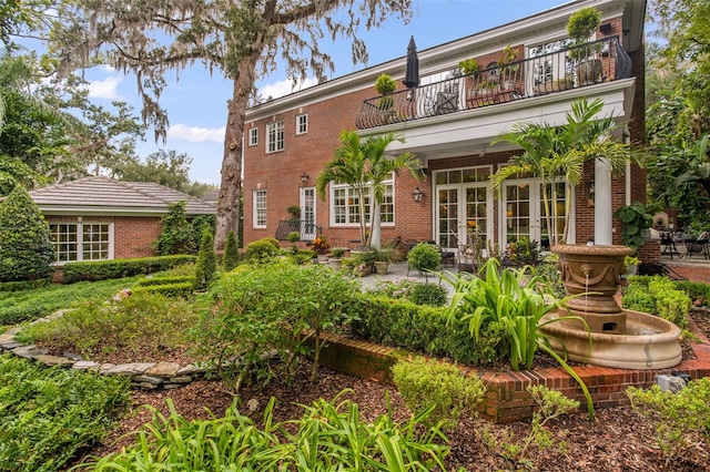 rear view of house featuring a balcony, a patio area, and french doors