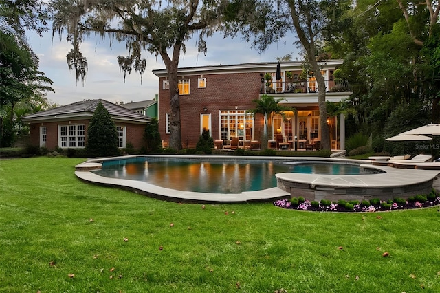 back of property featuring a balcony, a yard, and a patio area