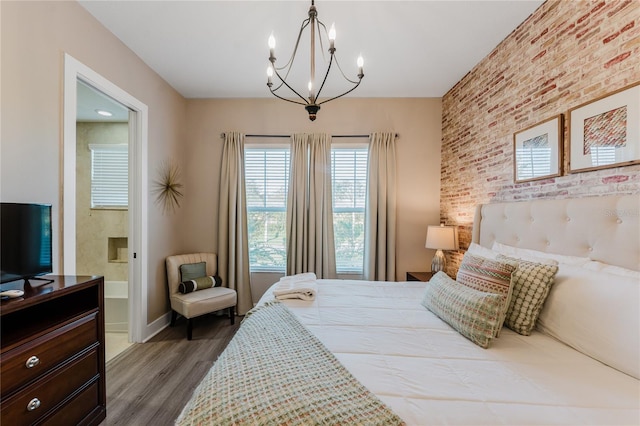 bedroom with brick wall, ensuite bathroom, a chandelier, and dark wood-type flooring