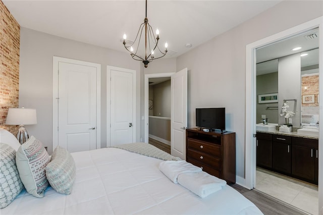 bedroom featuring an inviting chandelier, connected bathroom, and light hardwood / wood-style floors