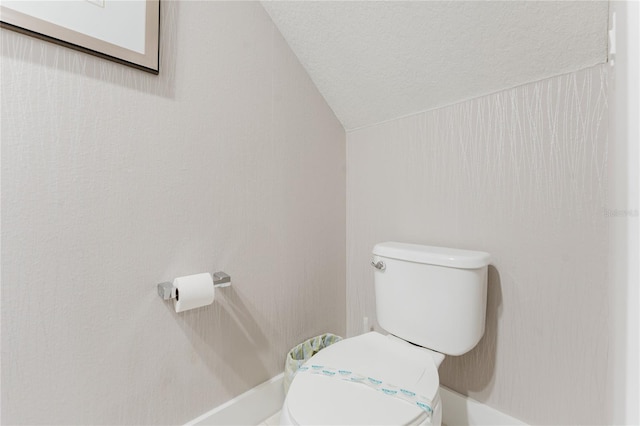 bathroom with toilet, a textured ceiling, and vaulted ceiling