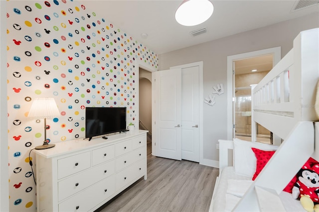 bedroom featuring light hardwood / wood-style flooring and ensuite bath