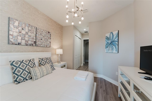 bedroom featuring an inviting chandelier and dark wood-type flooring