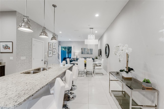 kitchen with sink, light stone counters, and decorative light fixtures