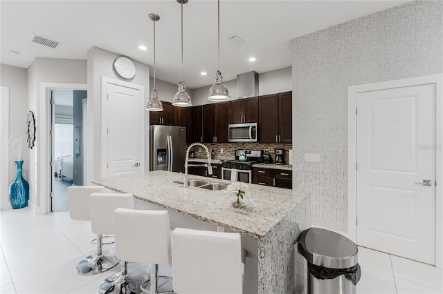 kitchen featuring a breakfast bar area, hanging light fixtures, dark brown cabinets, stainless steel appliances, and sink