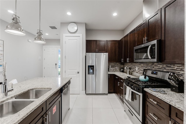 kitchen with light stone countertops, hanging light fixtures, stainless steel appliances, and backsplash