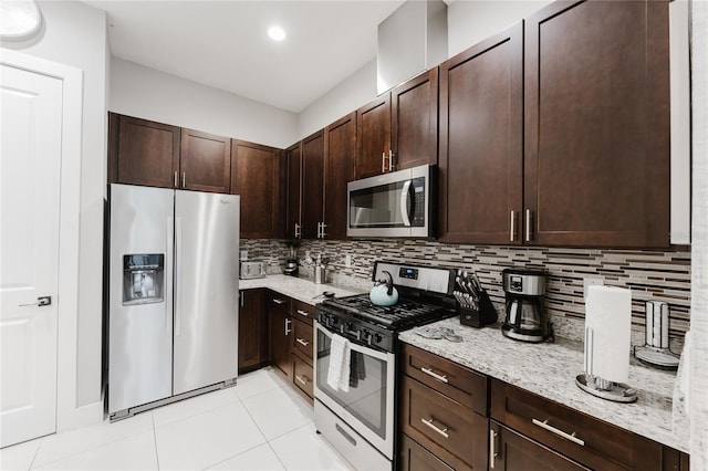 kitchen with decorative backsplash, stainless steel appliances, dark brown cabinets, light tile patterned flooring, and light stone counters