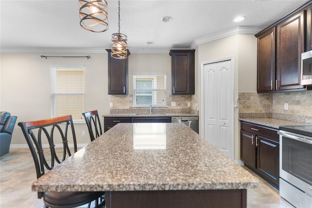 kitchen with light stone counters, ornamental molding, dark brown cabinets, appliances with stainless steel finishes, and a center island