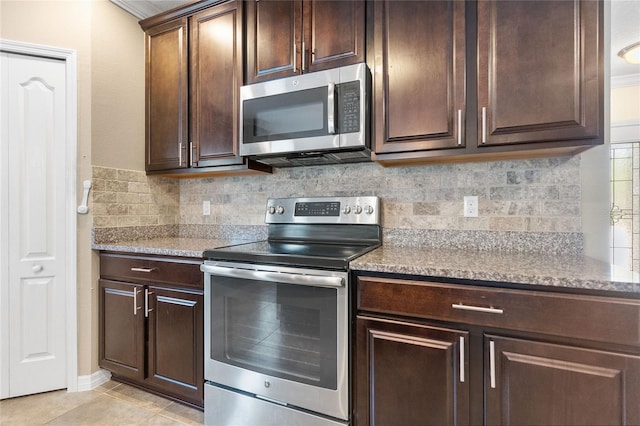 kitchen with backsplash, ornamental molding, light tile patterned floors, and stainless steel appliances