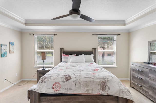 bedroom with ceiling fan, light colored carpet, a tray ceiling, and ornamental molding