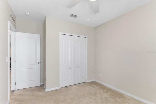 unfurnished bedroom featuring ceiling fan, light colored carpet, and a closet