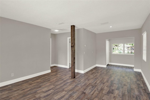 spare room featuring dark wood-type flooring and a textured ceiling