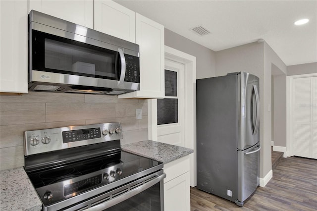 kitchen featuring light stone counters, appliances with stainless steel finishes, hardwood / wood-style floors, and white cabinets