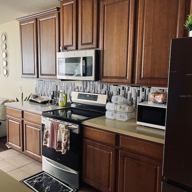 kitchen with stainless steel appliances, a textured ceiling, and light tile patterned floors