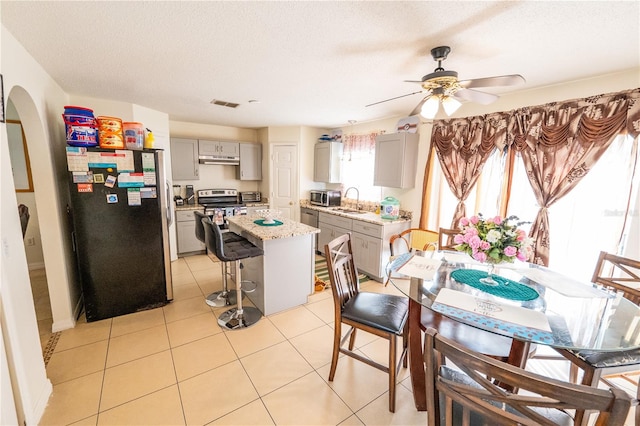 tiled dining area featuring ceiling fan, a textured ceiling, and sink