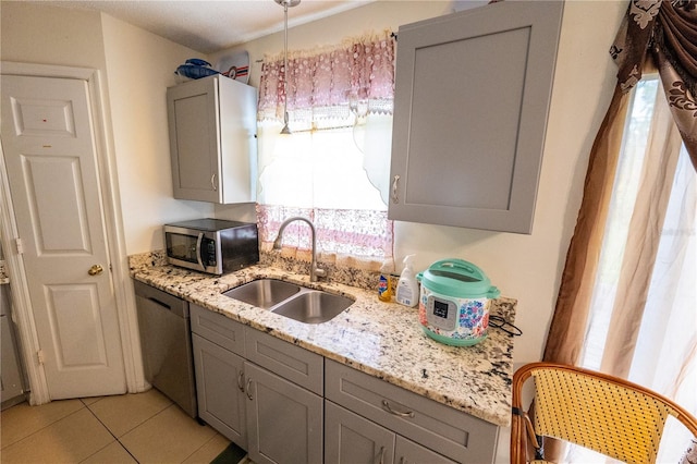 kitchen with appliances with stainless steel finishes, light stone countertops, sink, and gray cabinets