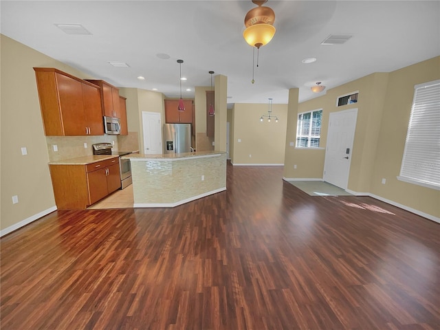 kitchen with hanging light fixtures, a kitchen island, dark hardwood / wood-style flooring, and stainless steel appliances