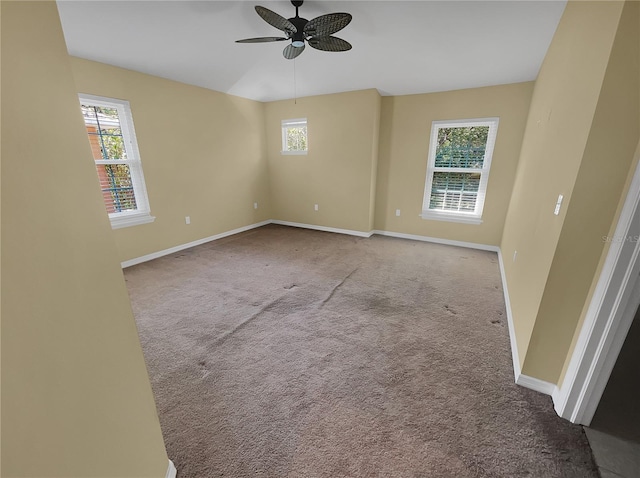 carpeted empty room with ceiling fan and plenty of natural light