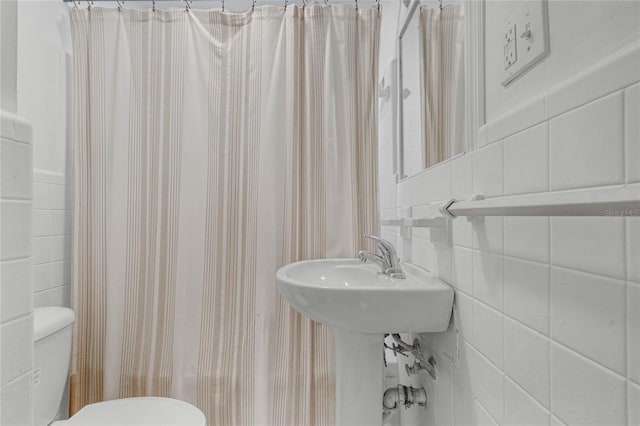 bathroom featuring tile walls, toilet, and shower / bathtub combination with curtain